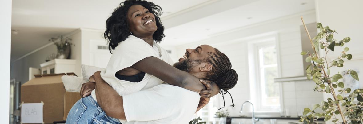 Man lifting woman in air happily in their new house