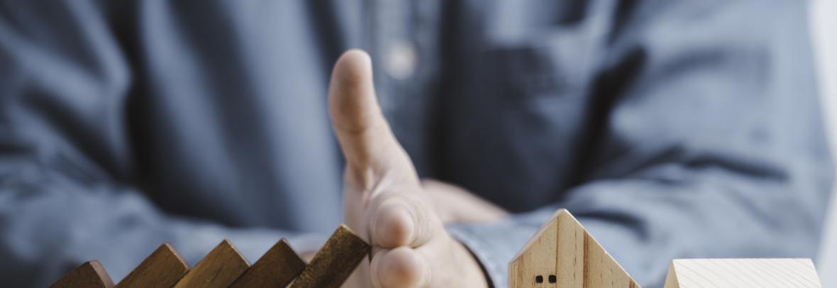 Businessman hand protect and stop wooden house from domino falling wooden bar for risk management and analysis of real estate concept. - stock photo