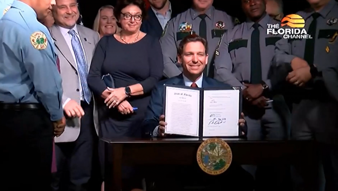 Gov. DeSantis holds up the copy of the Live Local law he signed