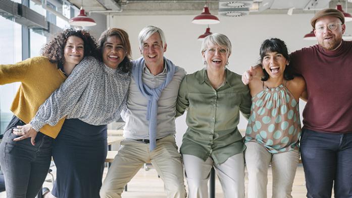 Photo of team of business people with arms around each others shoulders