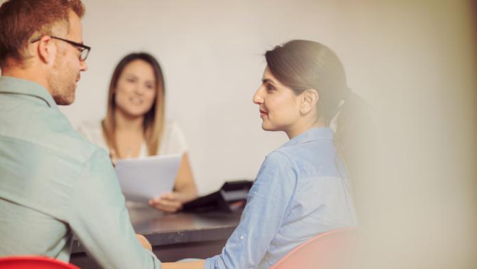 couple sitting with woman with paperwork
