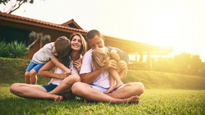 family sitting in yard outside a house
