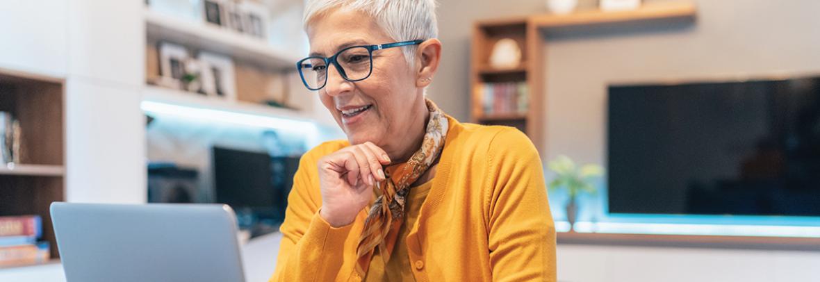 Senior woman working at home using lap top in the living room