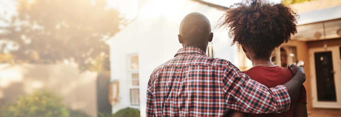 couple arm in arm looking at a house