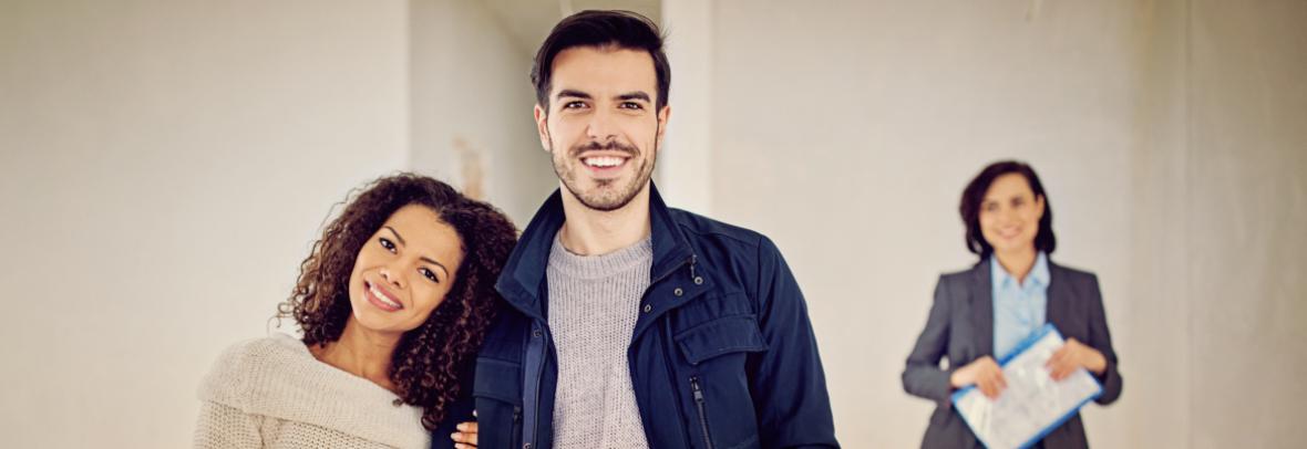 Smiling couple with Realtor in the background