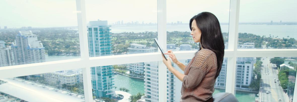 Woman with tablet in office overlooking city skyline
