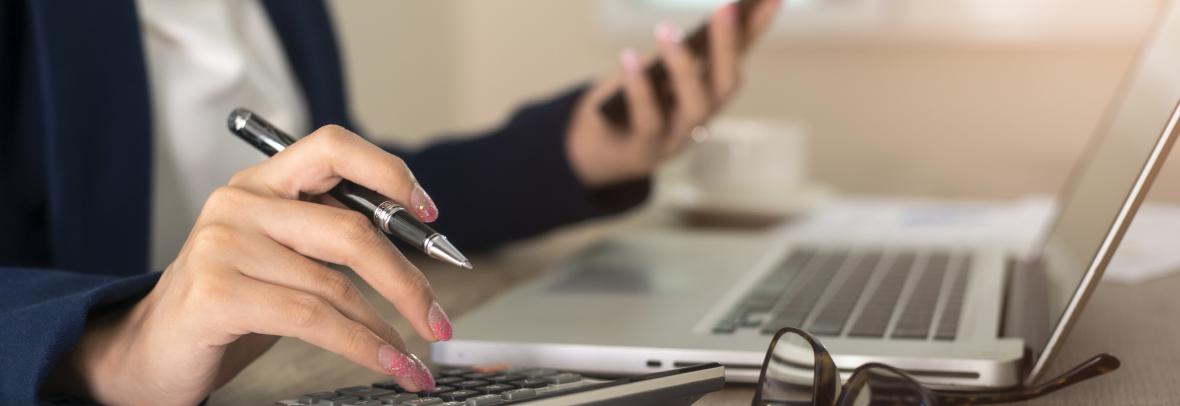 hands typing on calculator and laptop