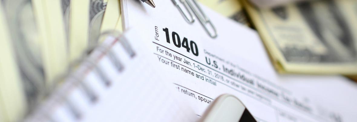 Tax form 1040 surrounded by paper and pens