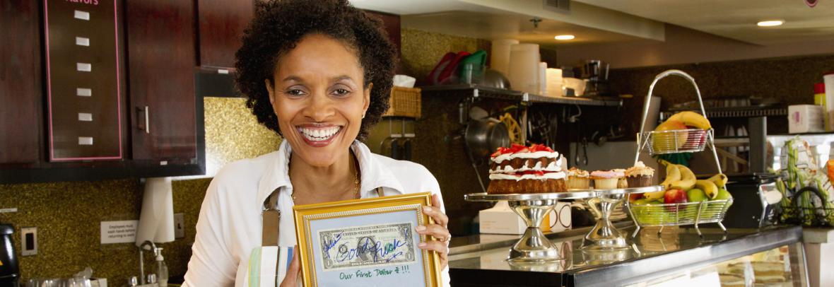 Bakery owner holding first dollar earned