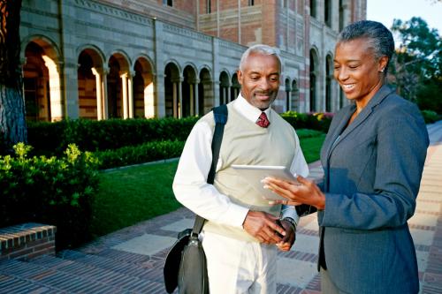 Two colleges professors looking at tablet while on campus