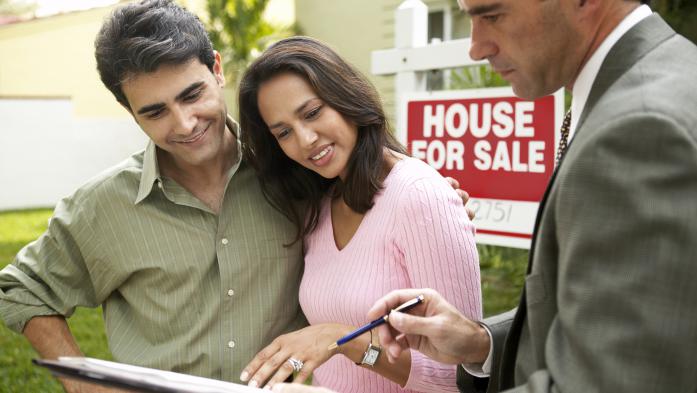  Couple and Real Estate Agent signing papers for new house
