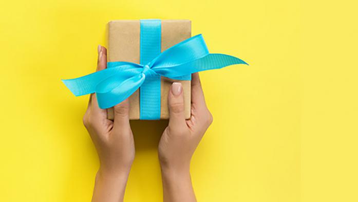 Hands holding gift on yellow background