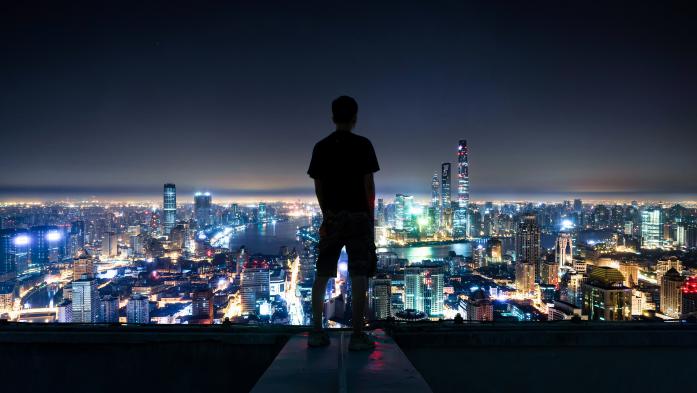 Man looking at nighttime skyline of Shanghai